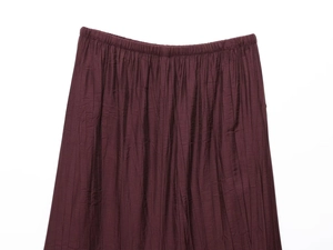 Detail of burgundy pleated skirt waist with textured fabric and elastic band