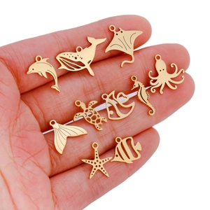 Set of 9 gold stainless steel ocean charms including dolphin and whale on hand palm