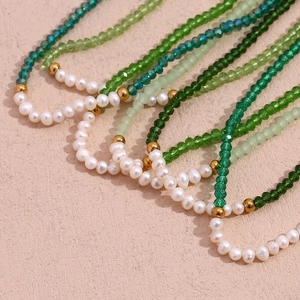 Detailed close-up of handmade necklace with green crystal beads and white freshwater pearls