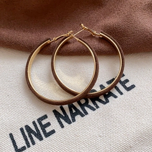 Detail of brown flocked circular earrings with gold metal accents on fabric background