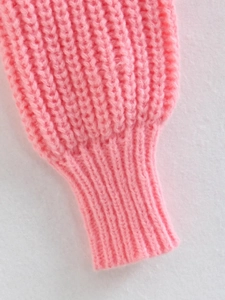 Dettaglio del polsino di un maglione rosa in maglia con trama a coste verticali