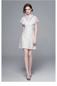 Détail de la robe beige avec motifs jacquard dorés et col en dentelle délicate et raffinée
