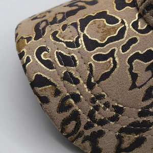 Macro detail of the faux suede baseball cap brim with golden leopard print and stitching