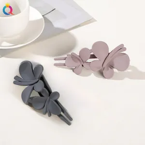 Detail view of matte butterfly hair clips in soft blue and pink resin on a clean background
