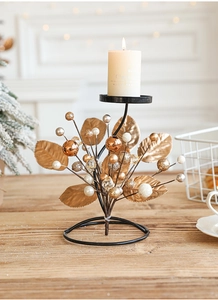 Close-up of iron Christmas candle holder with golden leaves and decorative ball ornaments