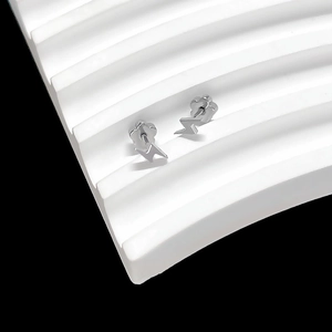 Detailed close-up of silver thunderbolt stud earrings on a wave display stand