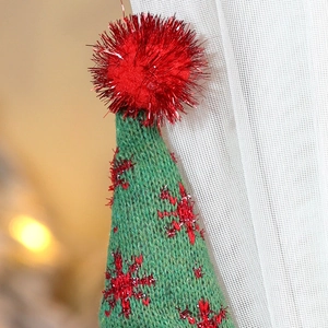 Detailed close-up of green knitted Christmas elf hat with red snowflake embroidery