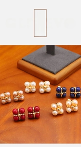 Flat lay of small pearl and gemstone flower stud earrings on warm wood surface
