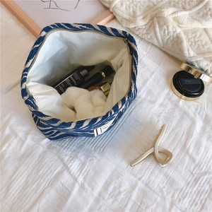Detail of blue striped chenille cosmetic bag showing spacious interior and zip closure