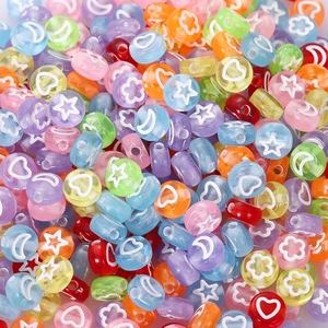 Macro shot of colorful acrylic beads featuring white stars and hearts for DIY jewelry