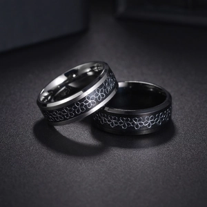 Matching set of two black and silver stainless steel rings with laser floral engravings