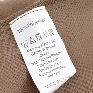 Detail of white laundry care label showing 100% polyester fabric and washing instructions
