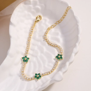 Detail of gold bracelet featuring green flower charms and adjustable lobster clasp on tray
