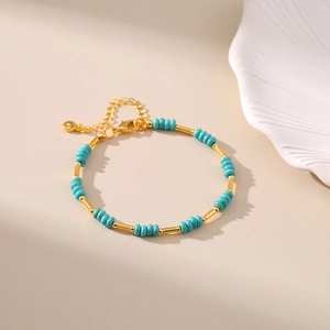 Detail of turquoise beaded bracelet with gold-plated tubes and adjustable clasp chain