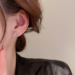 Close-up of a silver-toned knotted geometric earring with pavé-set cubic zirconia stones