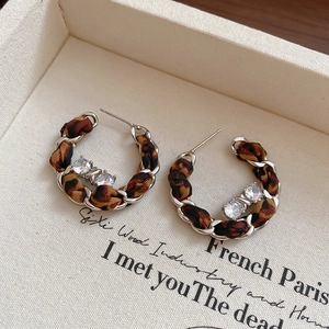 Gros plan de boucles d'oreilles C en tissu léopard tissé avec chaînes argent et zircons