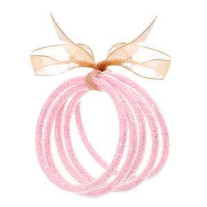 Dettaglio di bracciali morbidi con glitter rosa e fiocco in organza dorata