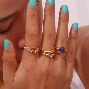 Close-up of stacked 18K gold-plated rings featuring colorful gemstones and curved designs
