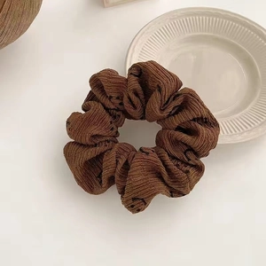 Detailed close-up of a brown corduroy hair scrunchie with minimalist smiley face prints