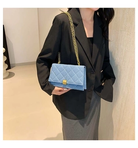 Blue denim crossbody bag with gold chain strap shown on black blazer suit detail