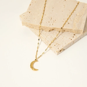 Textured gold moon pendant necklace on stone blocks, chic lava ripple crescent jewelry