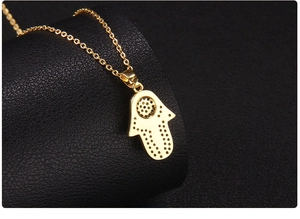 Macro shot of the back of a gold-plated Hamsa hand pendant showing intricate hole details