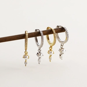 Close-up of gold and silver S925 earrings with sparkling cubic zirconia and white pearls