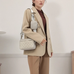 Minimalist light grey quilted crossbody bag with a wide strap and detachable coin pouch