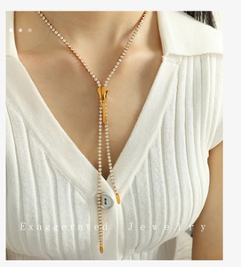 Detailed view of long gold zipper necklace with white zircons on a female model