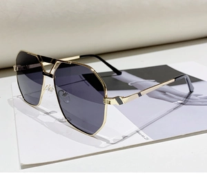 Detailansicht der goldenen polygonalen Pilotenbrille mit dunklen Gläsern auf einem Magazin