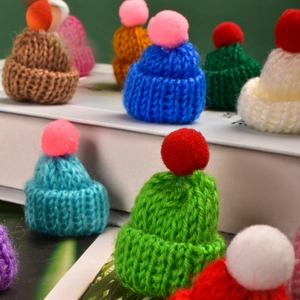 Close-up of colorful mini knitted Christmas hats with plush pom-poms for DIY crafts