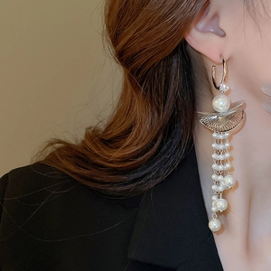 Close-up of elegant long pearl tassel earrings with fan-shaped gold metal on model