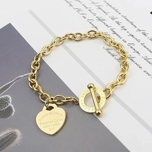 Detail shot of a gold heart charm bracelet with OT toggle clasp on a magazine background