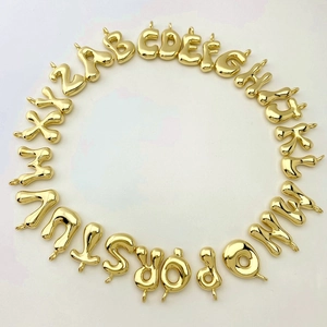 Macro view of 26 golden alphabet balloon pendants arranged in a circle on white background