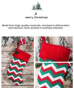 Macro detail of red and white chevron knitted Christmas stocking with pom-pom accents