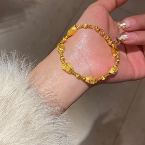 Detail of a gold irregular nugget bracelet with an adjustable O-ring clasp and chain