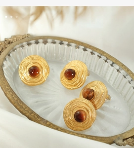 French vintage style gold earrings featuring tiger eye stone on retro glass tray