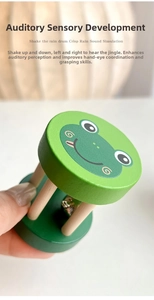 Macro shot of cartoon frog wooden rainmaker rattle with internal metal bells for baby