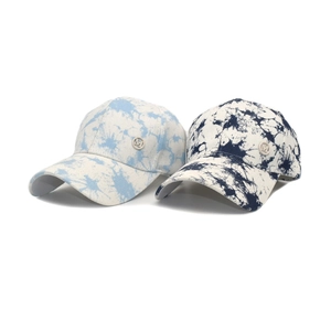 Detail of blue tie-dye cotton baseball caps with circular metallic M logo emblem