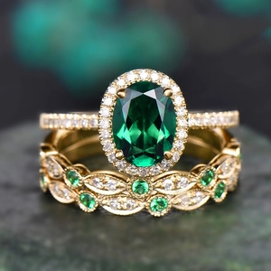 Detail shot of a gold-plated ring set featuring a green oval stone and leaf-shaped band