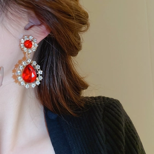Gros plan de boucles d'oreilles goutte en gemme rouge avec halo de diamants