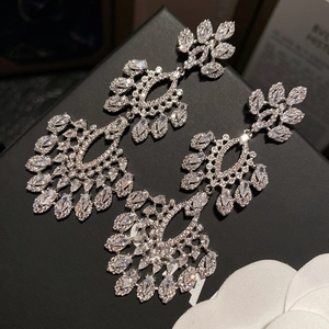 Gros plan de boucles d'oreilles fleuries en zircon sur présentoir noir et fleur blanche