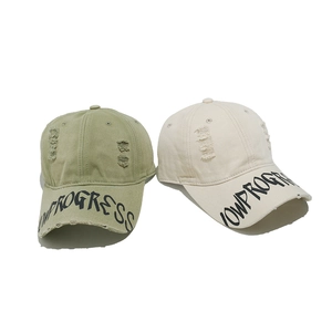 Detail of distressed baseball cap showing worn texture and NOWPROGRESS printing on brim