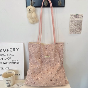 Close-up of pink tote bag featuring delicate white lace mesh and elegant pearl embellishments