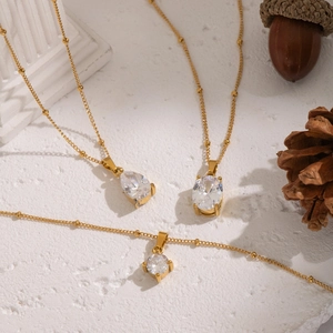Detailed close-up of oval and pear-shaped zircon pendants on gold necklaces with decor