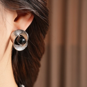 Close-up of silver twist earrings featuring a black bead on a female model