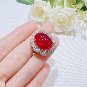 Red ruby pigeon blood ring with oval stone and diamond halo on model's hand