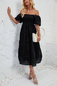 Detail of black tiered dress featuring grid jacquard fabric and smocked waist design