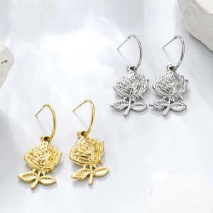 Detailed view of rose flower pendant earrings in gold and silver finish on stone