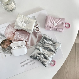 Detail of puffed bow-textured AirPods cases in silver, white, and pink with ring hooks